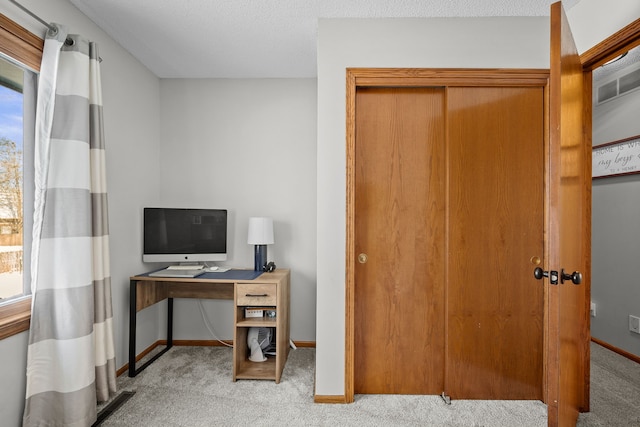 carpeted office space featuring a textured ceiling