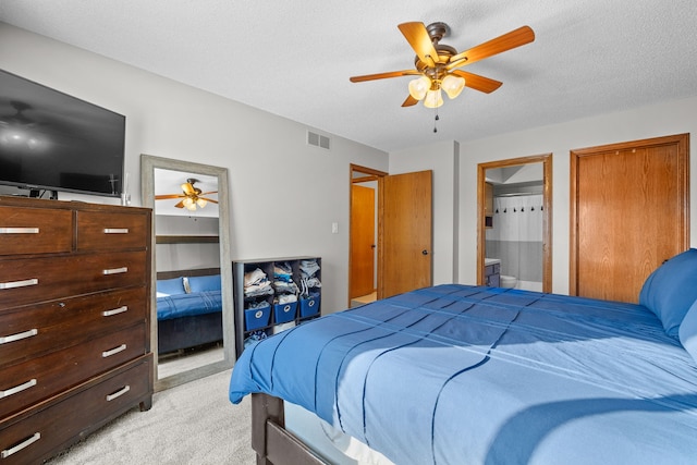 carpeted bedroom featuring ceiling fan, ensuite bath, and a textured ceiling