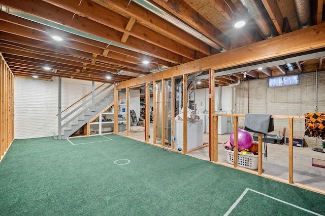 basement featuring brick wall, carpet flooring, and separate washer and dryer