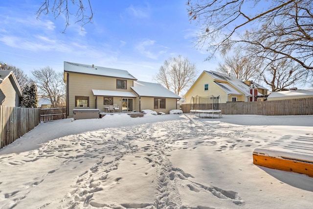 snow covered house featuring a hot tub and a trampoline