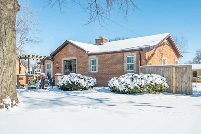 view of front of property with a chimney, fence, a pergola, and brick siding