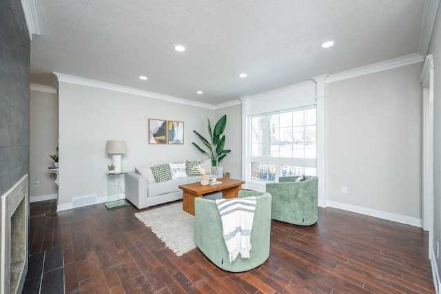 living room featuring baseboards, visible vents, dark wood-type flooring, a textured ceiling, and crown molding