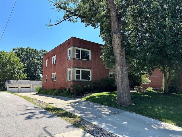 exterior space with a garage, an outbuilding, brick siding, and a front lawn