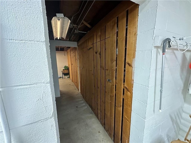 hall featuring concrete block wall and unfinished concrete floors