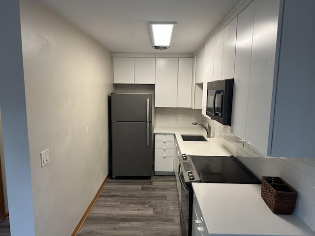 kitchen featuring dark wood-style flooring, stainless steel appliances, backsplash, white cabinets, and a sink