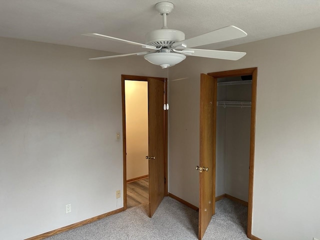 unfurnished bedroom with light carpet, a closet, a ceiling fan, and baseboards