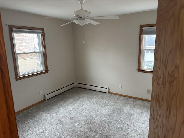 carpeted empty room featuring a baseboard heating unit, a wealth of natural light, and baseboards