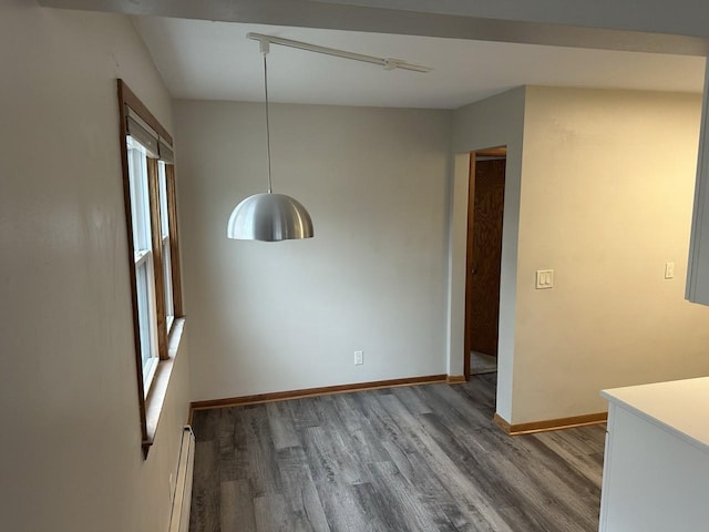 spare room with a baseboard heating unit, wood finished floors, and baseboards