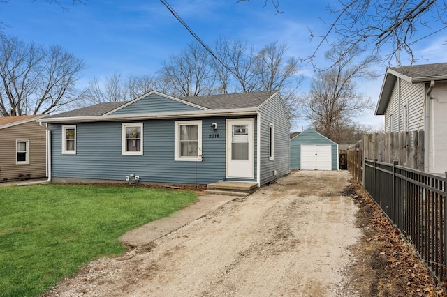 view of front facade featuring dirt driveway, a shingled roof, fence, an outdoor structure, and a front lawn