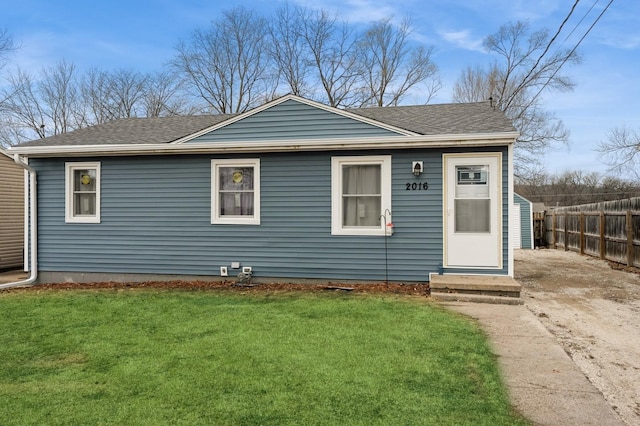 view of front of house with driveway, a shingled roof, fence, and a front yard