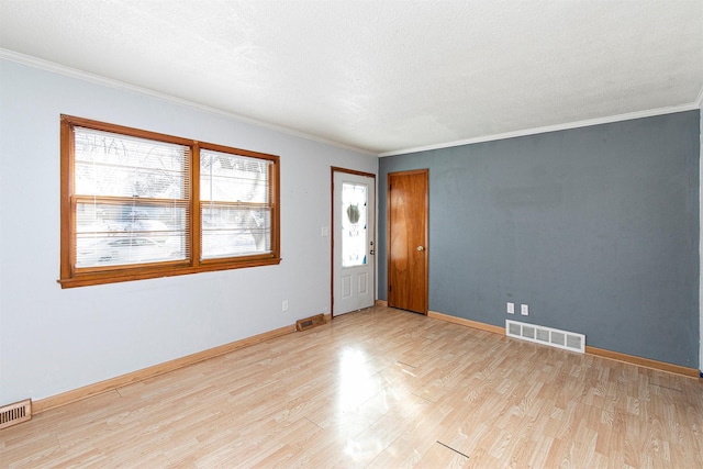 empty room with ornamental molding, light hardwood / wood-style floors, and a textured ceiling