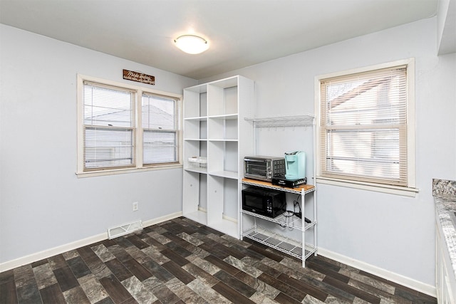 unfurnished office featuring plenty of natural light and dark hardwood / wood-style flooring