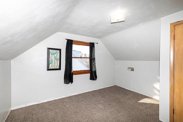 additional living space featuring vaulted ceiling, a textured ceiling, and carpet flooring