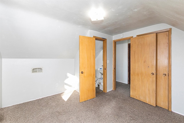 additional living space with dark colored carpet and vaulted ceiling