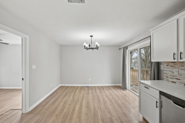 unfurnished dining area featuring an inviting chandelier, light hardwood / wood-style flooring, and a textured ceiling