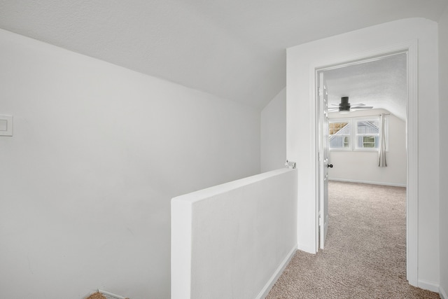 hallway with light colored carpet and vaulted ceiling