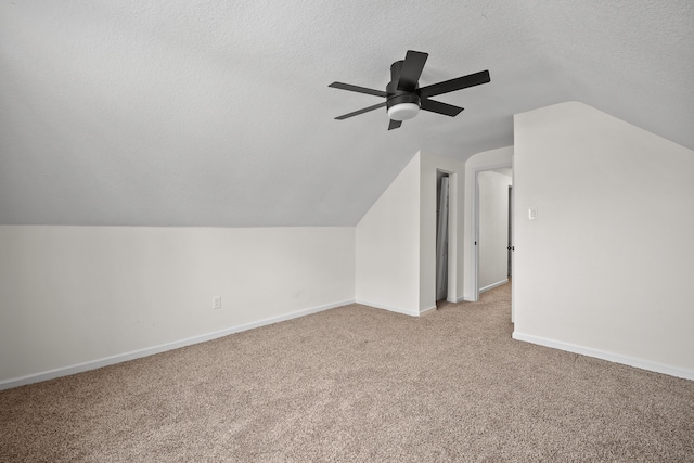 additional living space with light carpet, ceiling fan, vaulted ceiling, and a textured ceiling