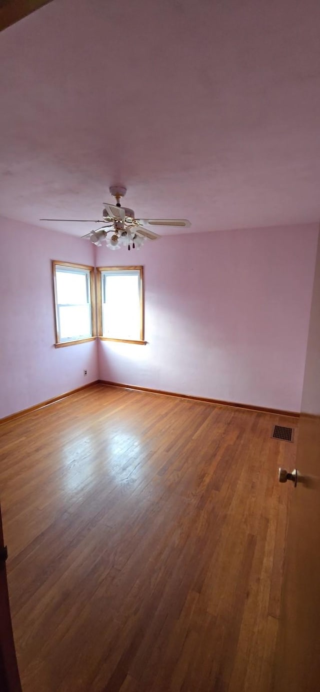 spare room featuring ceiling fan, wood finished floors, and visible vents