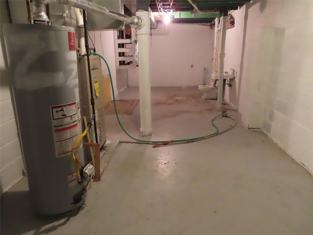 unfinished below grade area featuring water heater and concrete block wall