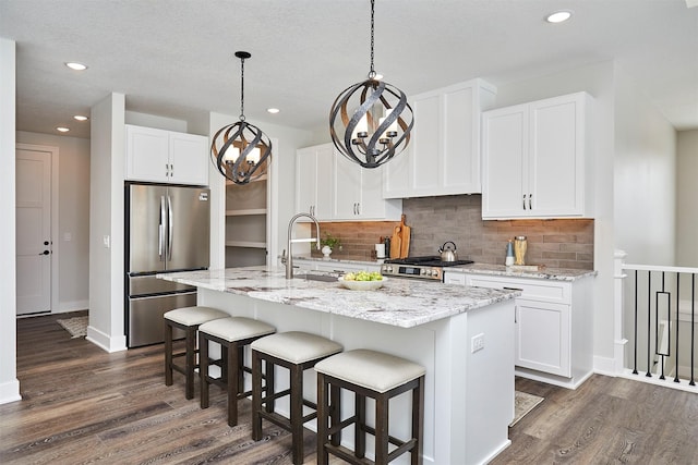 kitchen featuring tasteful backsplash, white cabinetry, stainless steel appliances, and dark wood-style flooring