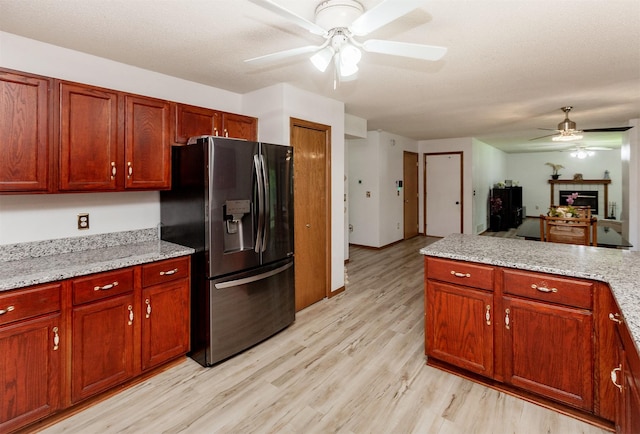 3015 Deerpath Ct, Des Moines, IA 50320 - kitchen featuring stainless steel fridge, a ceiling fan, light wood-style flooring, a fireplace, and light stone counters