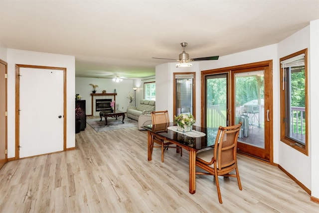 3015 Deerpath Ct, Des Moines, IA 50320 - dining room featuring light wood-style floors, a tiled fireplace, and a ceiling fan