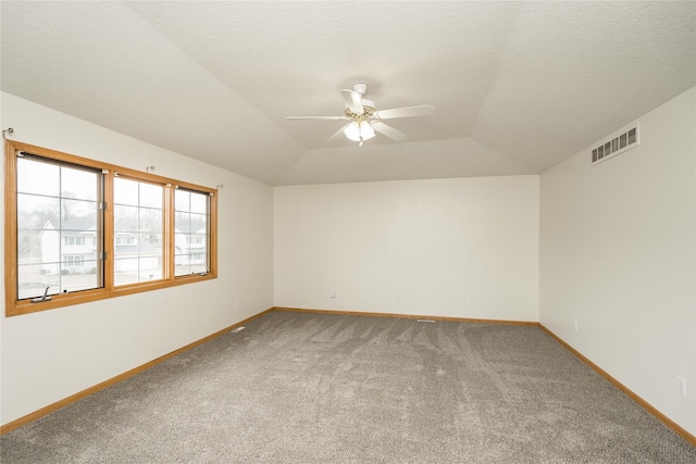 spare room with lofted ceiling, carpet, ceiling fan, a raised ceiling, and a textured ceiling