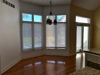 unfurnished dining area featuring hardwood / wood-style flooring, a wealth of natural light, and an inviting chandelier