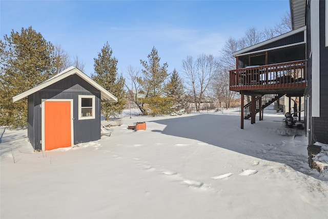 yard covered in snow with stairway, a shed, an outdoor structure, and a deck