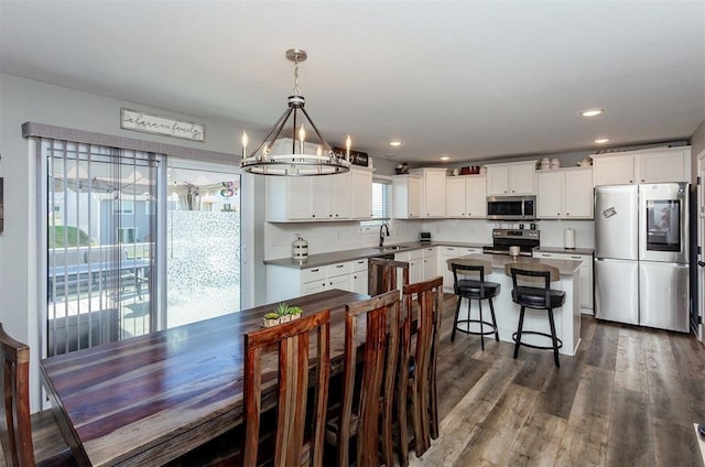 dining space featuring sink, a notable chandelier, and dark wood-type flooring