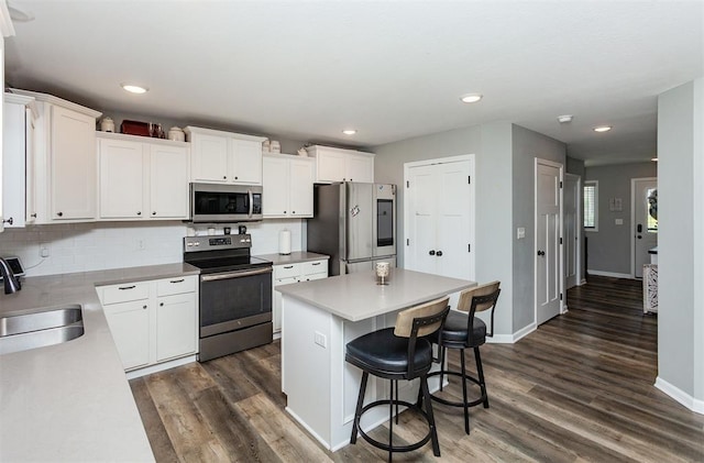 kitchen featuring sink, dark wood-type flooring, appliances with stainless steel finishes, a center island, and white cabinets