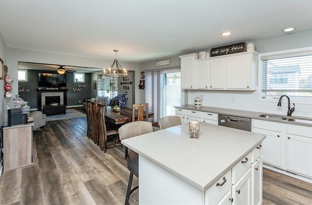 kitchen featuring sink, white cabinetry, decorative light fixtures, a center island, and dishwasher