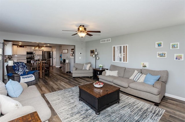 living room featuring dark wood-type flooring and ceiling fan with notable chandelier