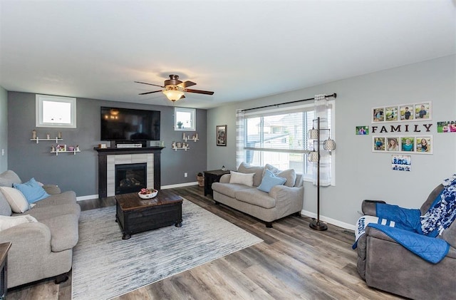 living room featuring a tile fireplace, hardwood / wood-style floors, and ceiling fan