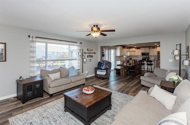 living room with dark wood-type flooring and ceiling fan with notable chandelier