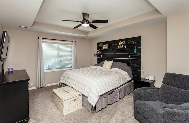 carpeted bedroom featuring a raised ceiling and ceiling fan