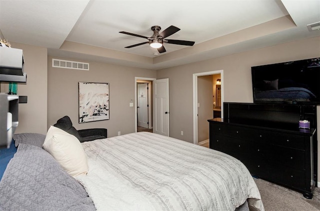 bedroom featuring a tray ceiling, light colored carpet, and ceiling fan