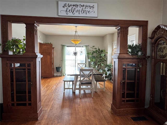 dining area featuring hardwood / wood-style flooring and ornate columns