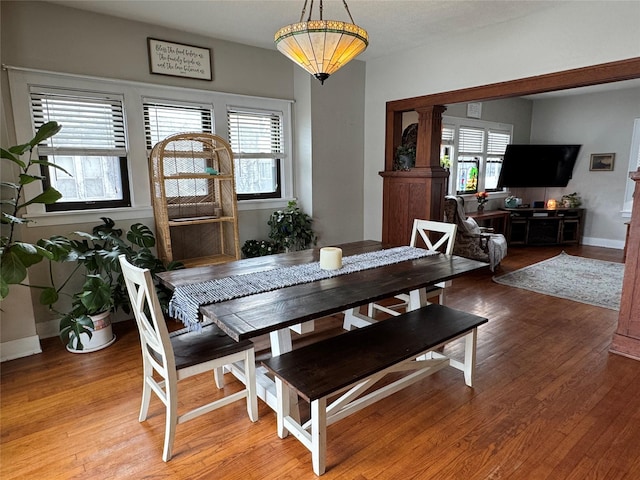 dining space with hardwood / wood-style flooring and ornate columns