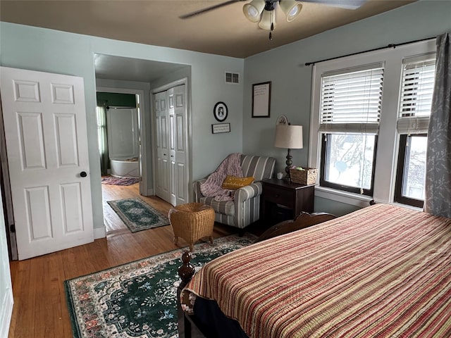 bedroom with ceiling fan, ensuite bathroom, hardwood / wood-style floors, and a closet