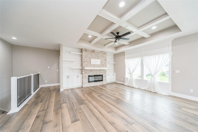 2938 NE Brentwood Cir, Grimes, IA 50111 - unfurnished living room with light wood-style floors, coffered ceiling, a ceiling fan, beam ceiling, and a stone fireplace