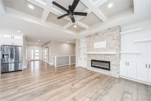 2938 NE Brentwood Cir, Grimes, IA 50111 - unfurnished living room featuring coffered ceiling, light wood-type flooring, ceiling fan, beamed ceiling, and a stone fireplace