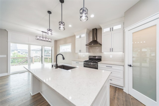 2938 NE Brentwood Cir, Grimes, IA 50111 - kitchen featuring wall chimney range hood, stainless steel range with gas cooktop, a kitchen island with sink, decorative backsplash, and white cabinetry