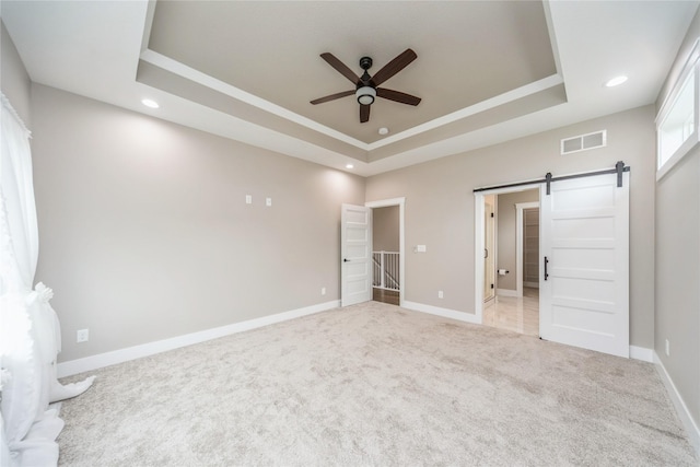 2938 NE Brentwood Cir, Grimes, IA 50111 - unfurnished bedroom with a tray ceiling, a barn door, light colored carpet, recessed lighting, and a ceiling fan