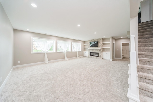 2938 NE Brentwood Cir, Grimes, IA 50111 - unfurnished living room featuring light carpet, stairway, a stone fireplace, and recessed lighting