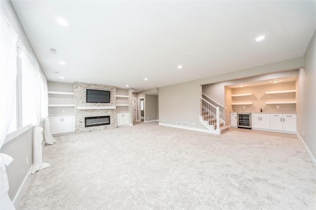 2938 NE Brentwood Cir, Grimes, IA 50111 - unfurnished living room featuring wine cooler, light colored carpet, a fireplace, bar area, and recessed lighting