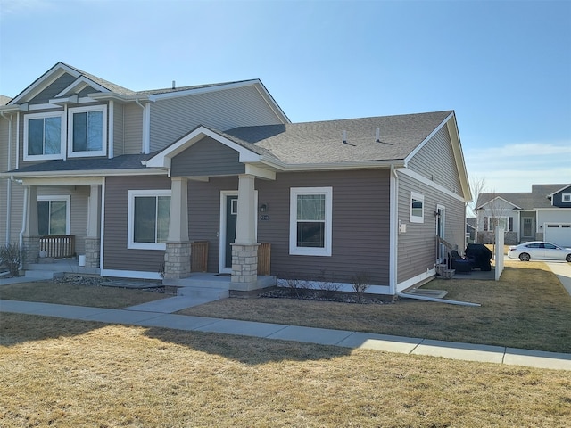 view of front facade featuring a front yard and a shingled roof