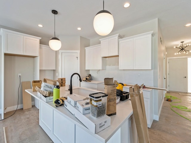 kitchen with white cabinetry, decorative light fixtures, tasteful backsplash, and a center island with sink