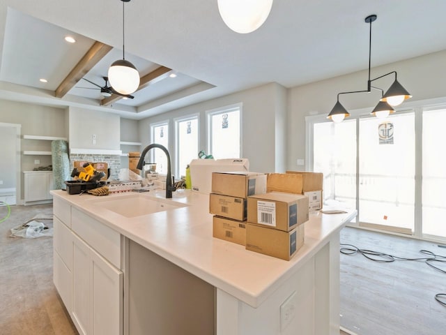 kitchen with pendant lighting, sink, a large island, ceiling fan, and white cabinetry