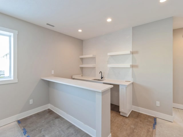 kitchen featuring kitchen peninsula, sink, and white cabinets